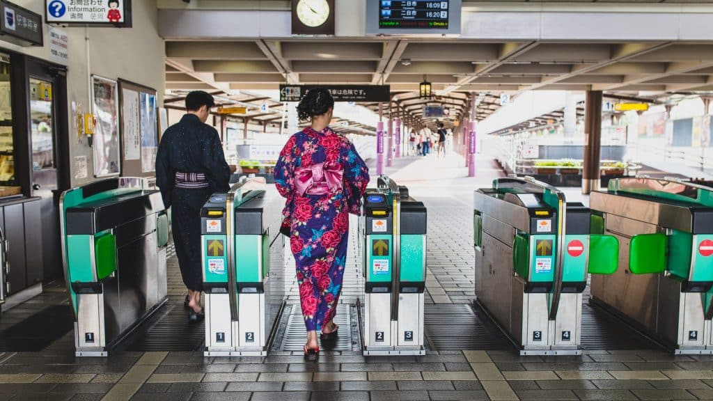 Two people in kimono passing through automatic ticket gates in Japan