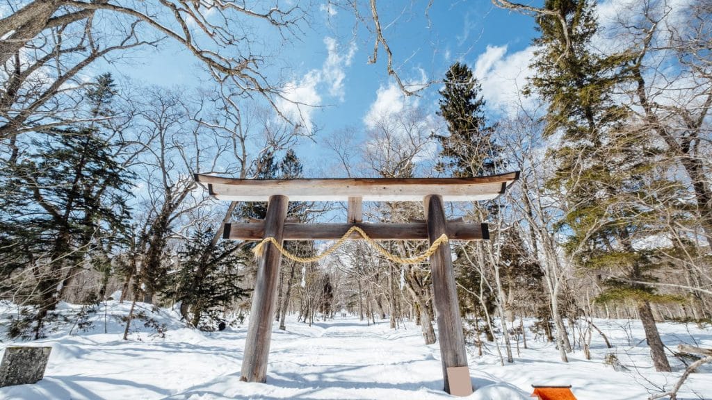 A wooden torii gate at a shrine entrance in falling snow