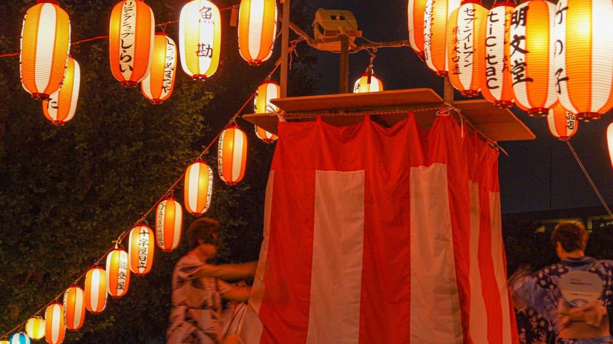 Paper lanterns strung above a stall at a Bon Odori summer festival