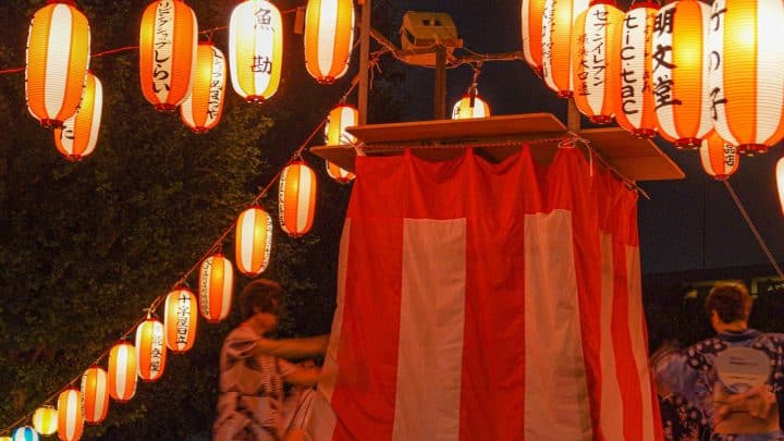Paper lanterns strung above a stall at a Bon Odori summer festival