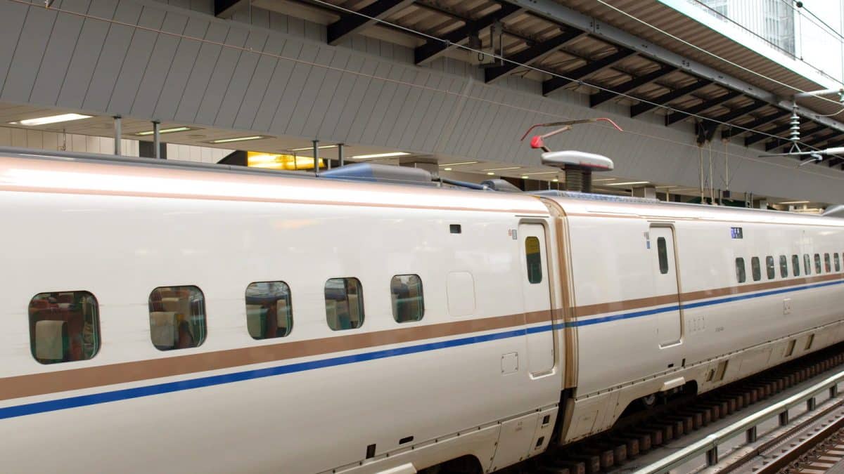A white Shinkansen bullet train departing a Tokyo Station platform