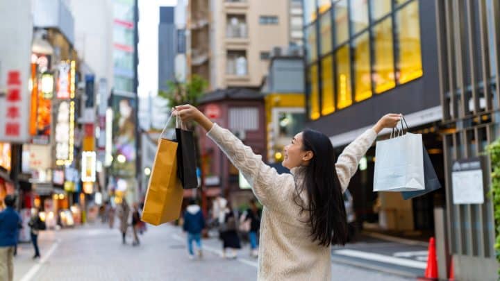 A shopper carrying a paper bag on a shopping street in Shibuya, Tokyo
