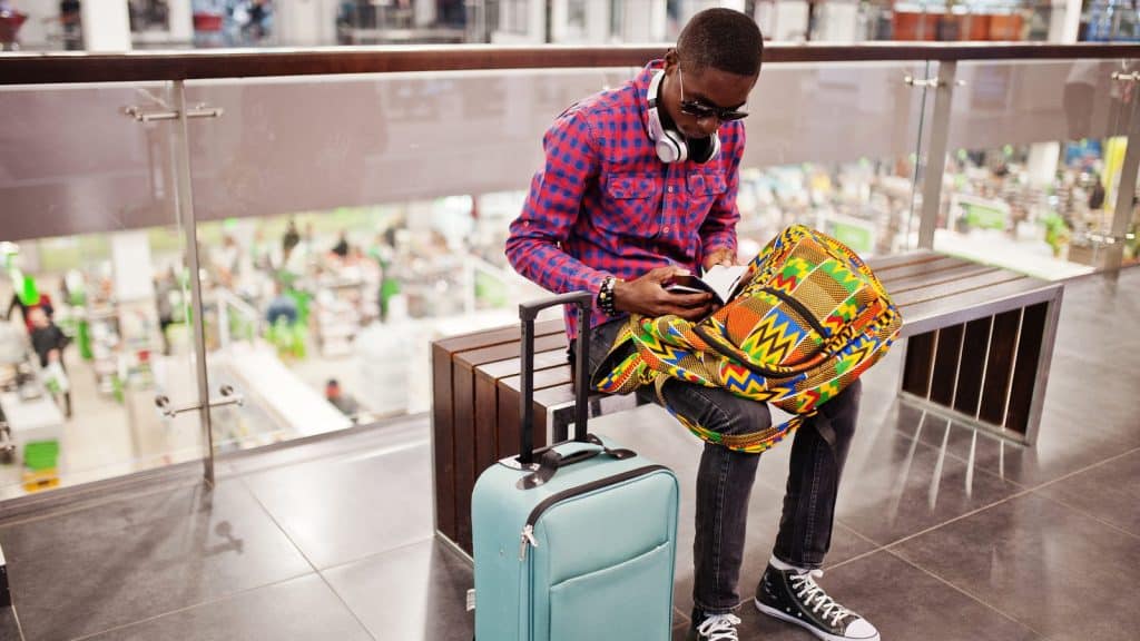 A traveller with a suitcase checking a passport in an airport duty-free area