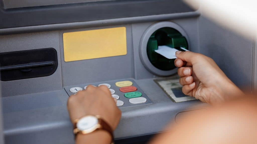 A woman typing a PIN while withdrawing money from a cash machine