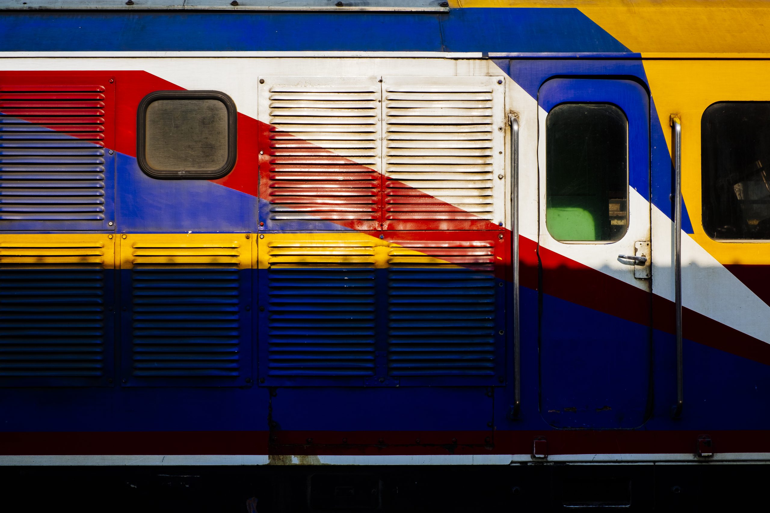 Side view of a Thai passenger train standing at a station