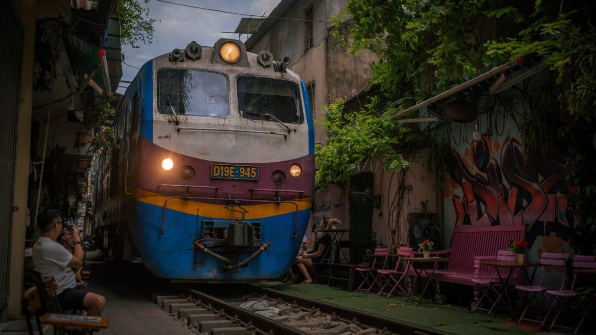 Passenger train squeezing through a narrow residential street in Hanoi