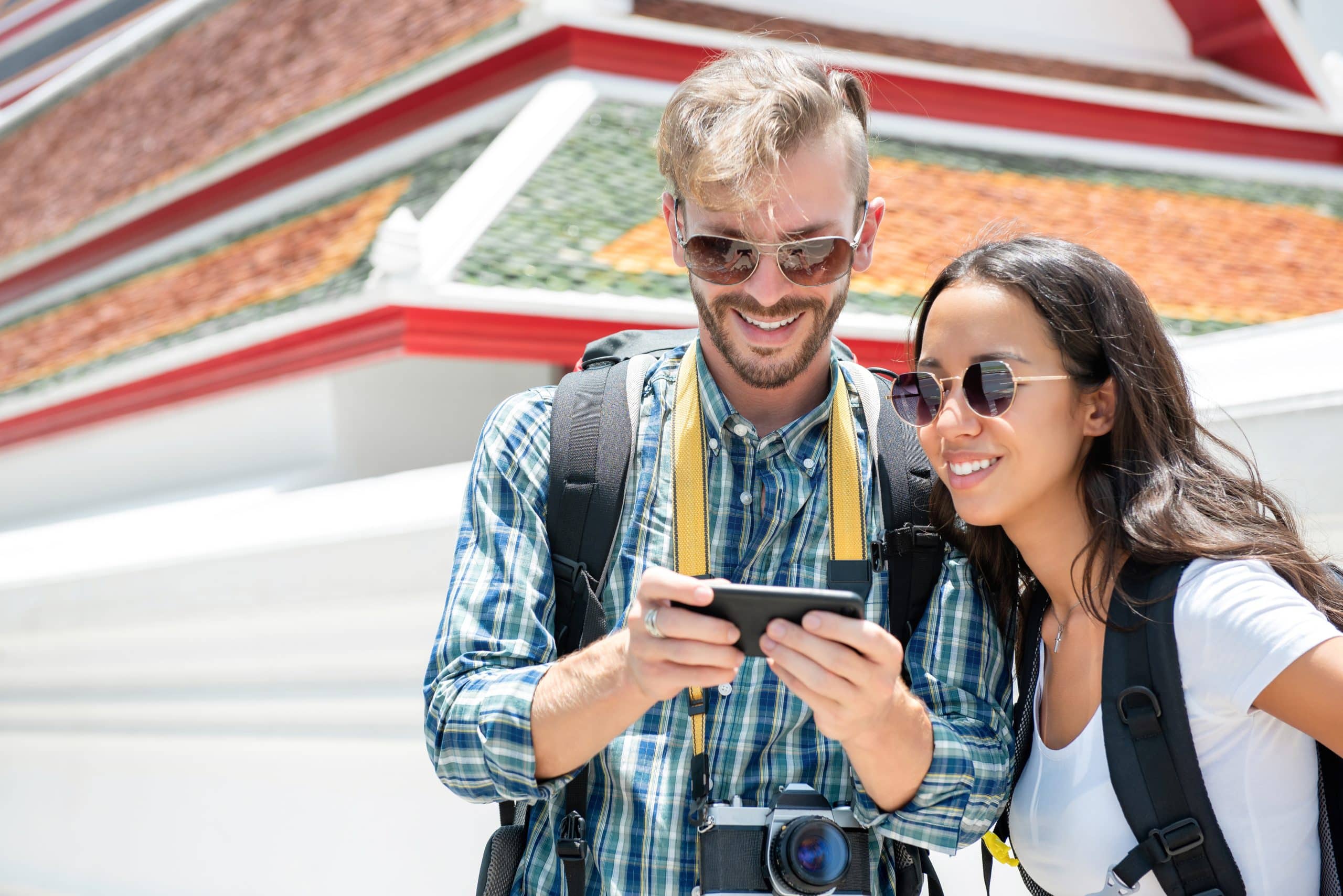 Two backpackers checking directions on a smartphone while traveling in Thailand