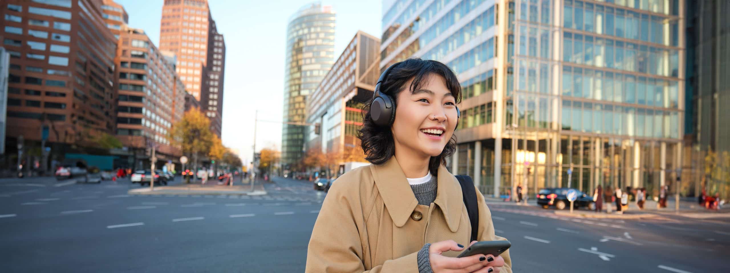 Young woman walking through a Korean city centre with a smartphone and headphones