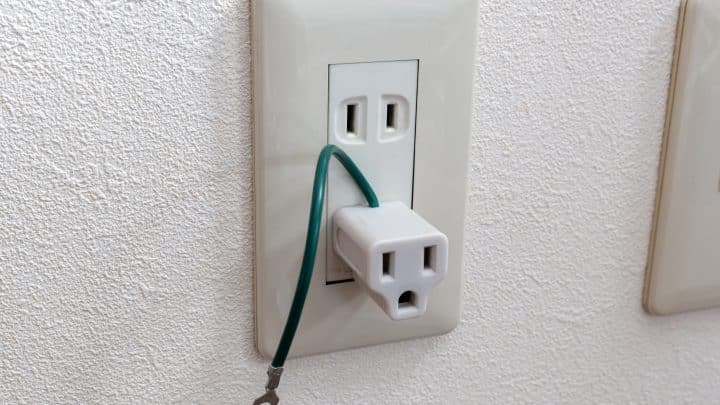 Travel adapter plugged into a two-slot Type A outlet on a hotel room wall in Japan
