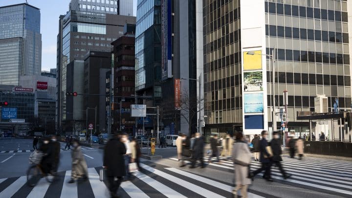 Pedestrians crossing a busy Tokyo street at a marked crosswalk