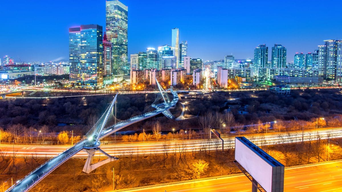 Evening traffic on a Seoul expressway with the city skyline lit up behind