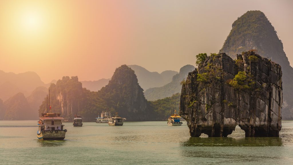 Tourist junk boats sailing between limestone karsts in Ha Long Bay