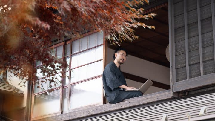 Remote worker sitting on the engawa of a traditional Japanese room, laptop on lap