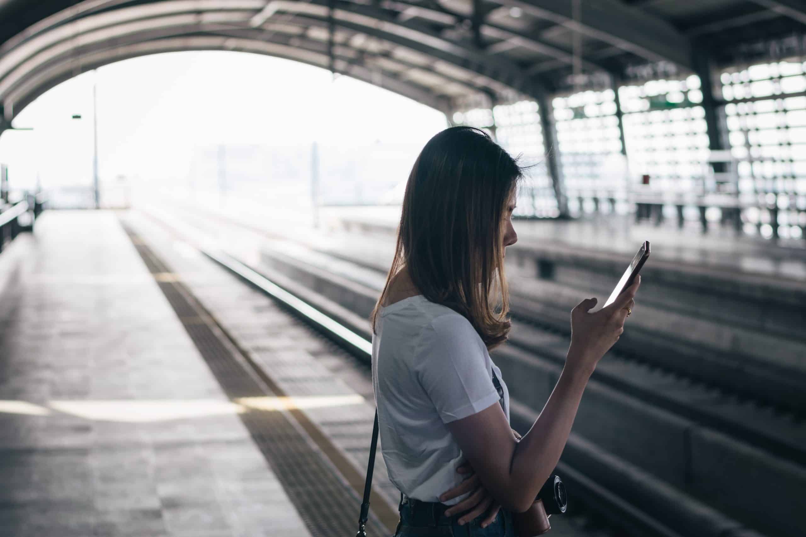 Passenger waiting on an Airport Rail Link platform in Bangkok and checking her phone
