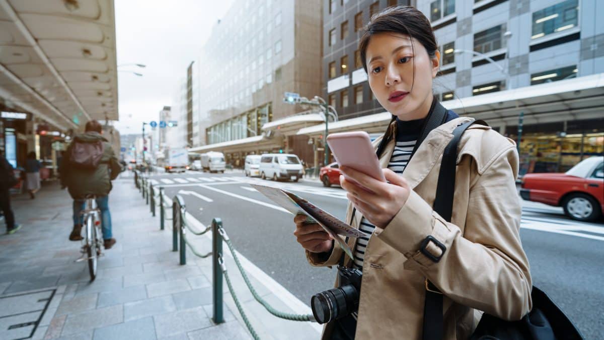 Traveller at a Seoul bus stop checking a map app on her phone