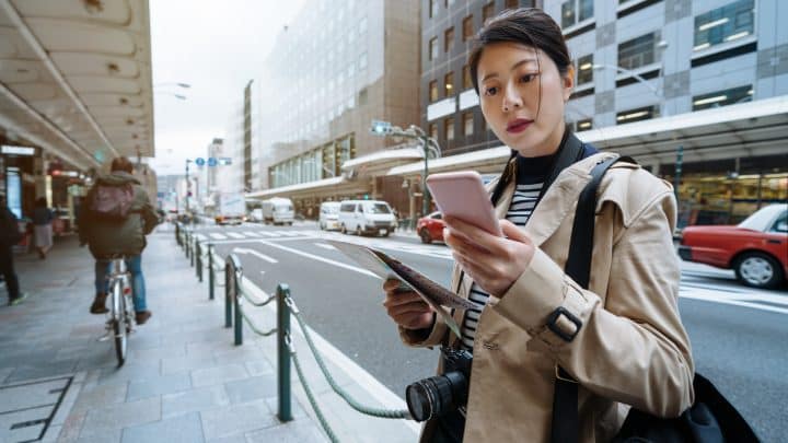 Traveller at a Seoul bus stop checking a map app on her phone