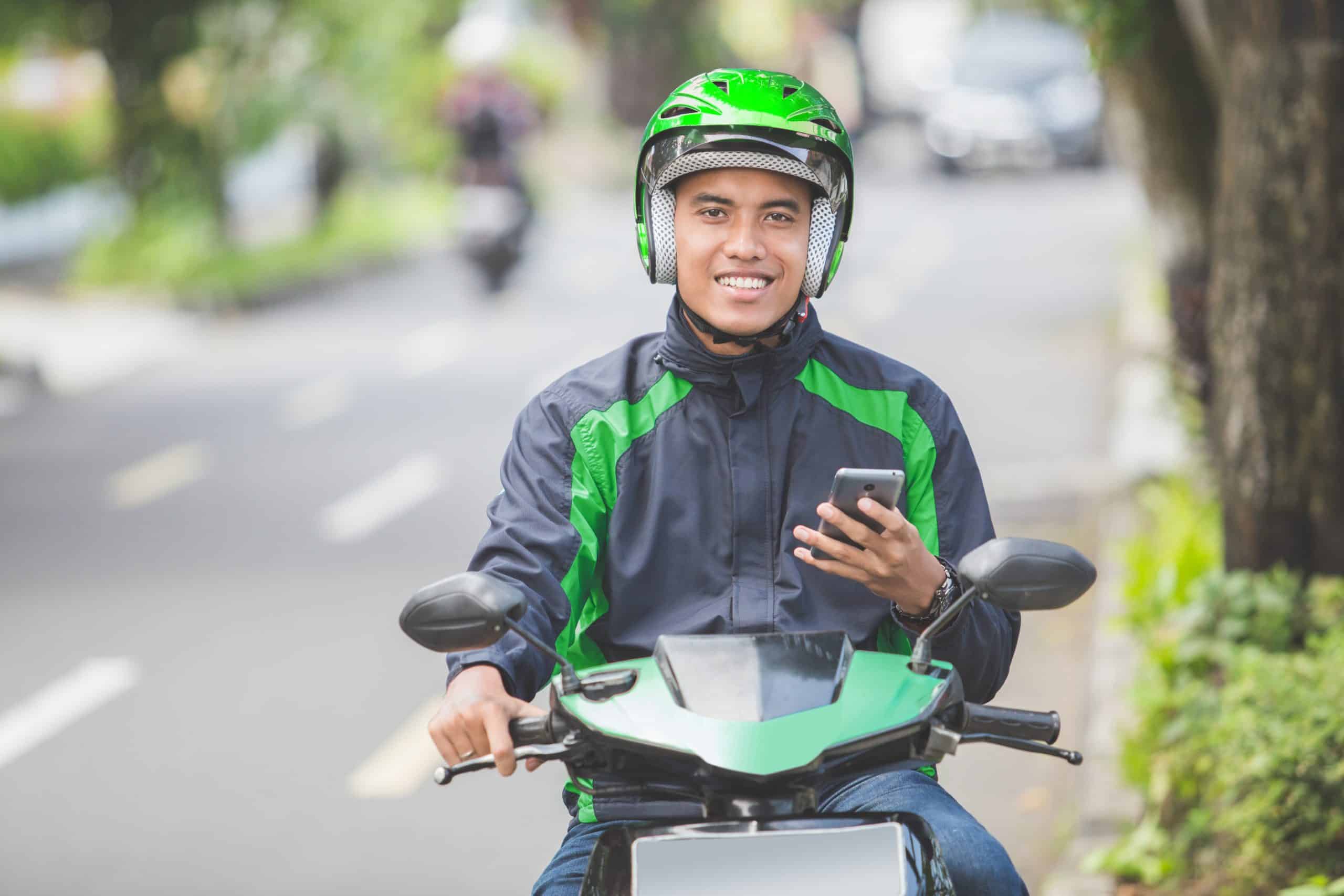 Motorbike taxi driver accepting a booking in a ride-hailing app
