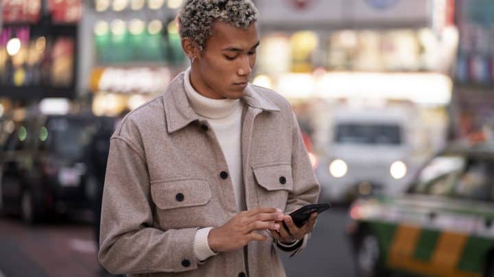 A traveler in a busy Tokyo shopping street checking his smartphone for a roaming signal