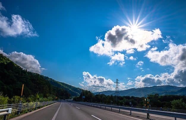 A curved elevated expressway winding through green hills in Hokkaido, Japan