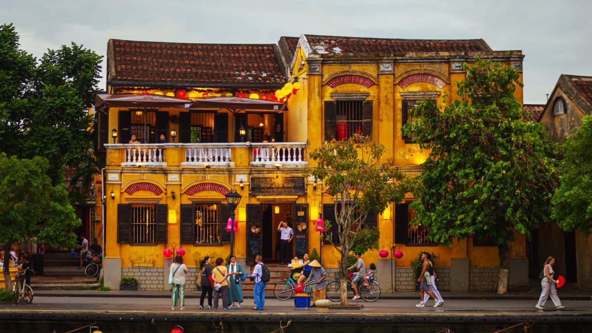 Yellow historic houses, boats and silk lanterns along the embankment of Hoi An ancient town at sunset