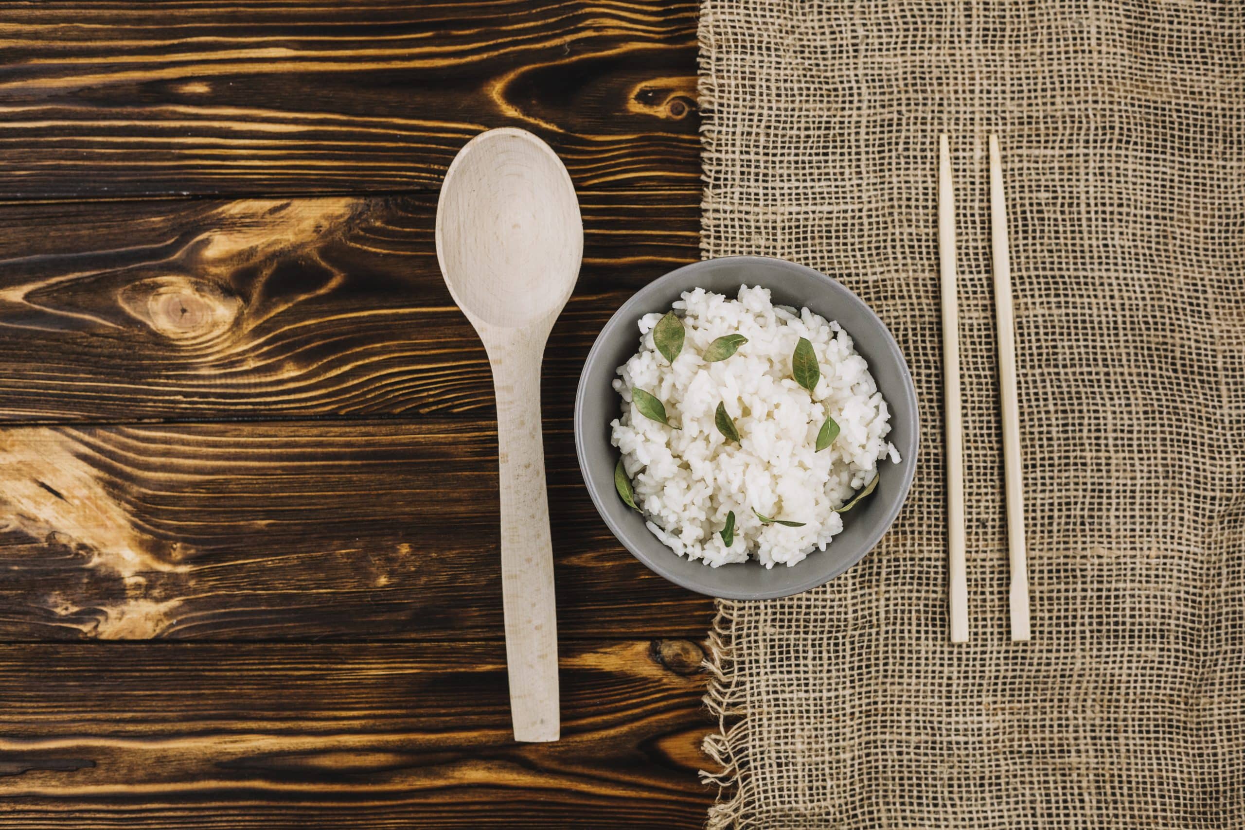 Chopsticks and a spoon beside a bowl of boiled rice