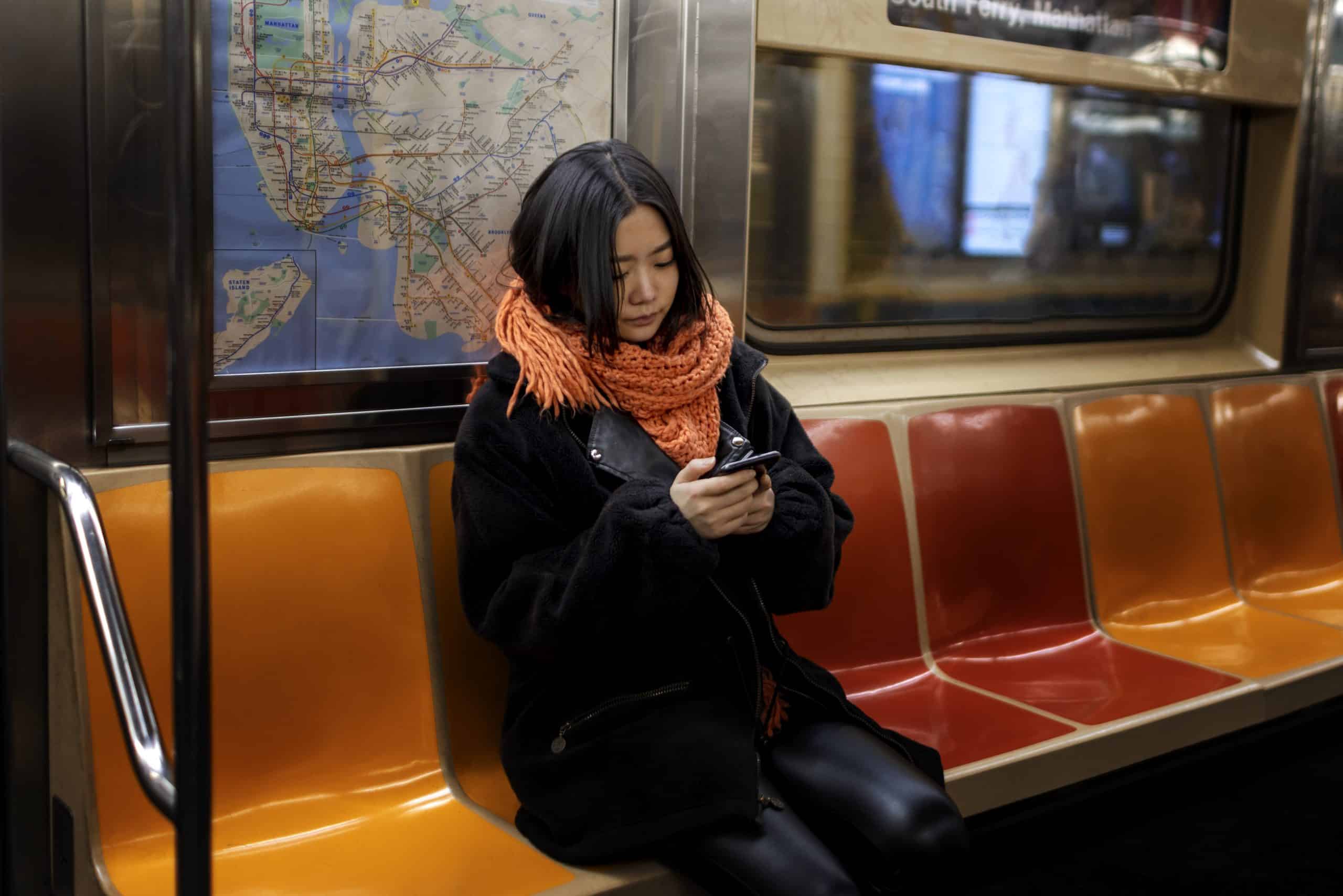 Woman looking at her smartphone while riding a subway train