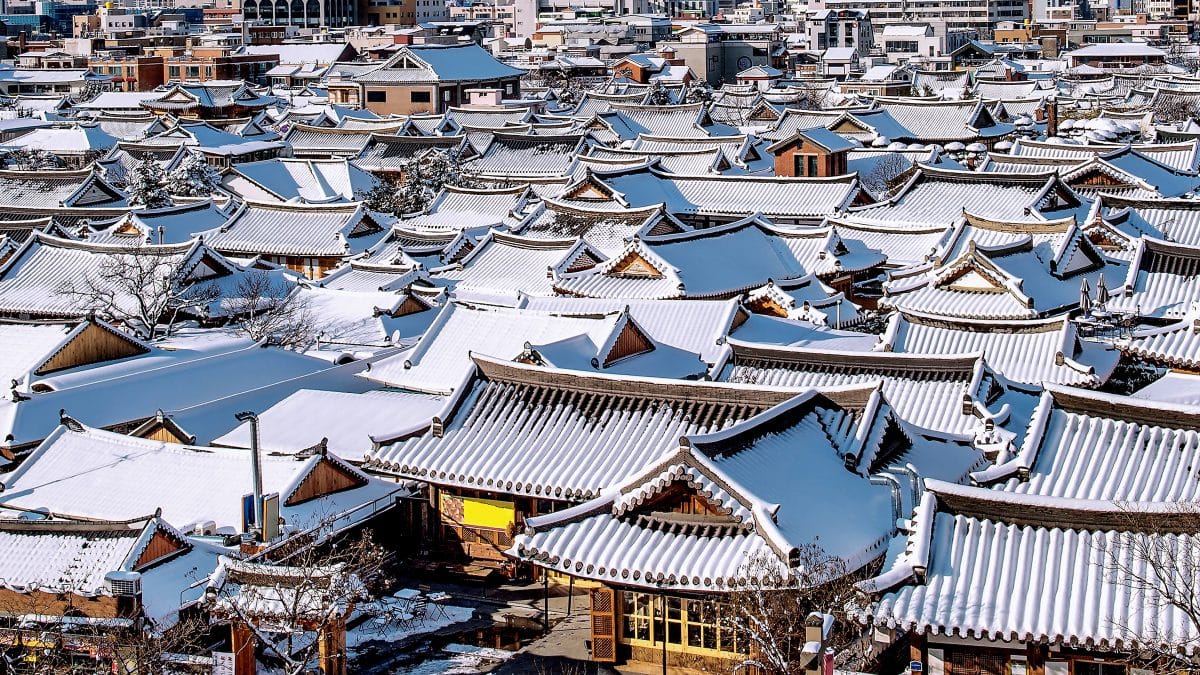 Curved tiled roofs of traditional hanok houses covered in snow in Jeonju Hanok Village