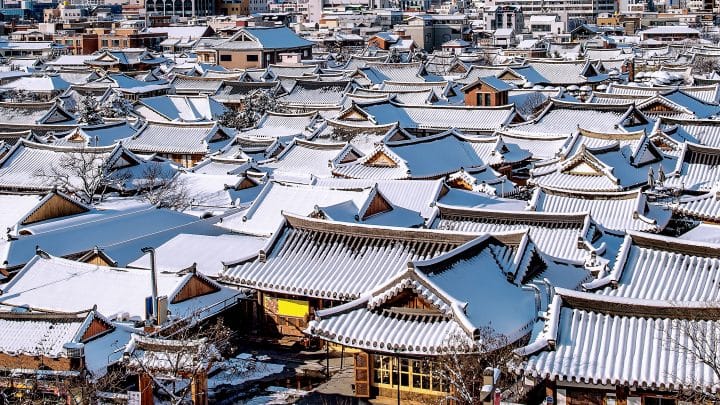 Curved tiled roofs of traditional hanok houses covered in snow in Jeonju Hanok Village