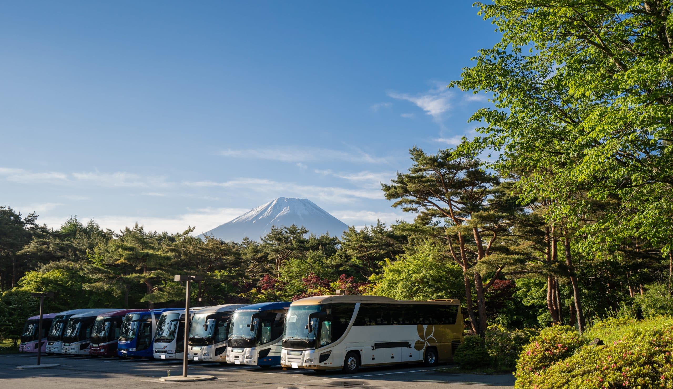 Shuttle bus parking lot at the base of the Fuji Subaru Line with Mount Fuji's summit visible in the early morning light