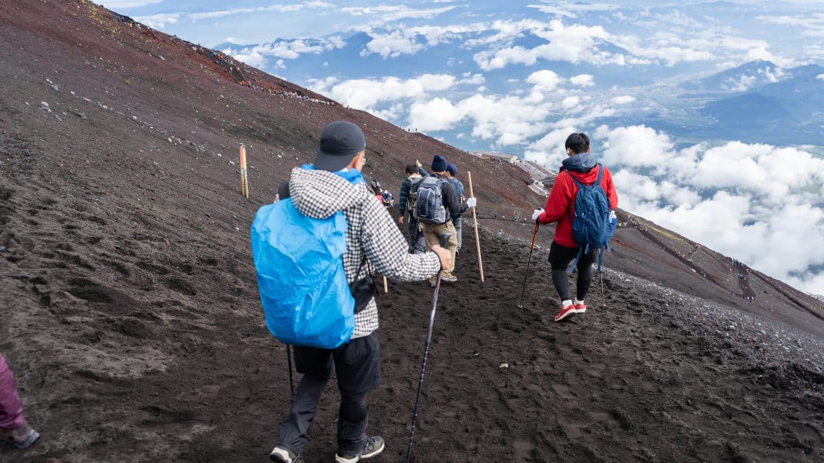 Line of hikers climbing the volcanic scree slope of Mount Fuji's Yoshida Trail during the official climbing season
