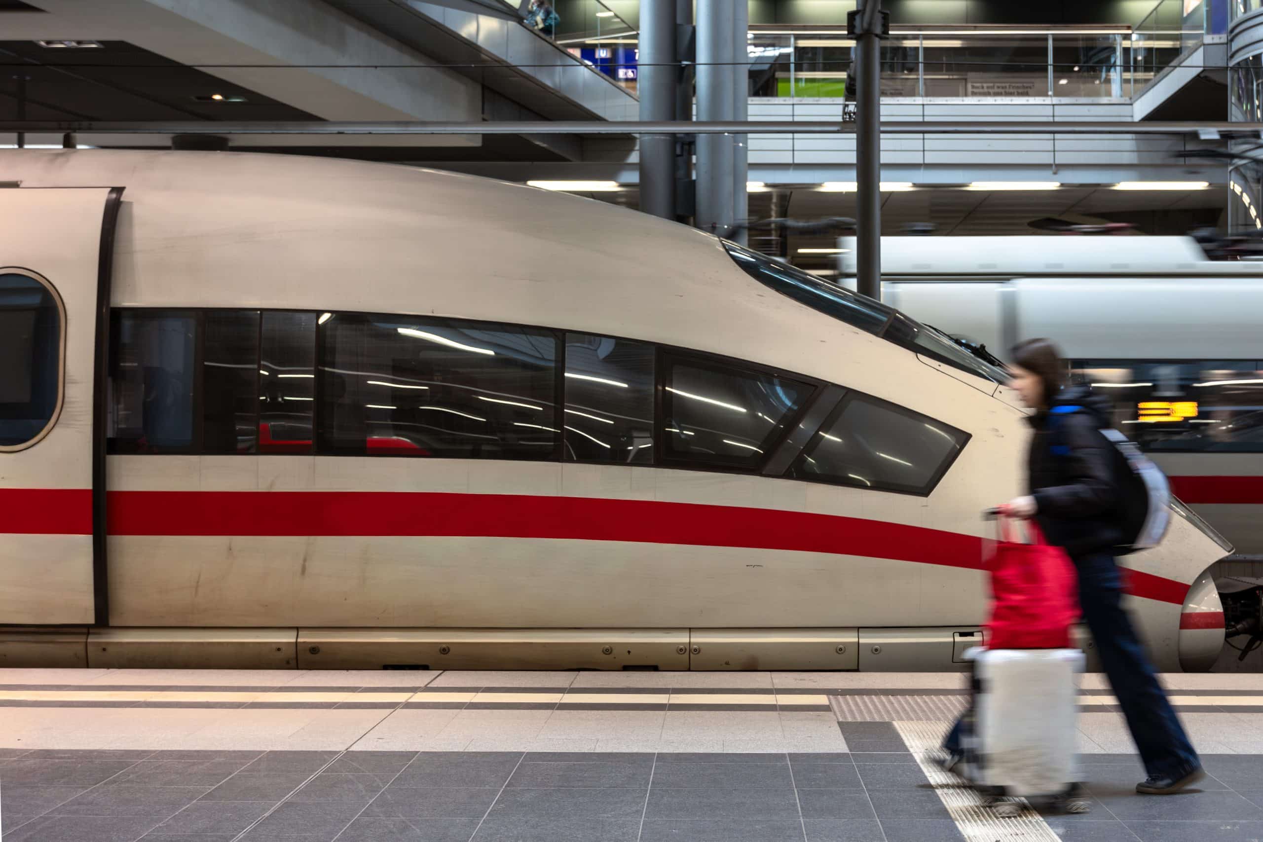 High-speed train at a station platform with a passenger walking past